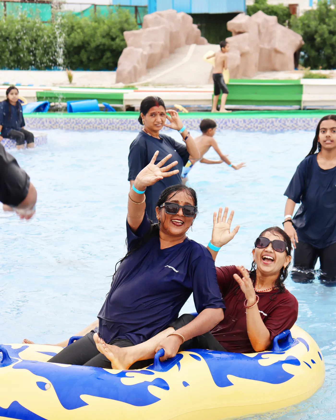 Two visitors laughing as they ride a double tube in the pool